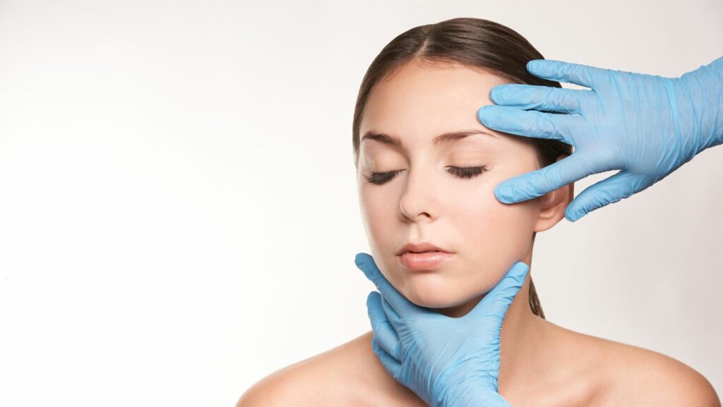 Frauengesicht mit zwei Händen in blauen OP - Handschuhen kurz vor der Anwendung eines Facelifts - ein kritisches Interview mit Prof. Dr. Frank Peter, Beauty Pro, Praxis am Wittenbergplatz Berlin